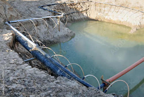 The process of lowering the groundwater level. Industrial sand quarry and a metal tube around it with thin tubes directed at the ground.