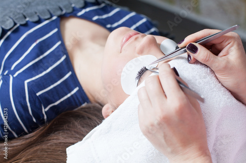 beautician making artificial lashes. eyelash extension procedure  photo