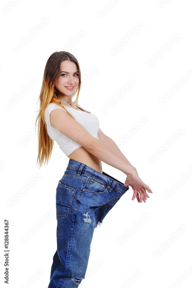 pretty girl jeans with large size enjoys a slim figure. Weight Loss. slim  girl in a loose fitting on a white background Stock Photo | Adobe Stock