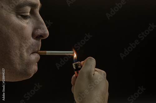 Man smoking cigarette on black background. Mystery man with cigarette