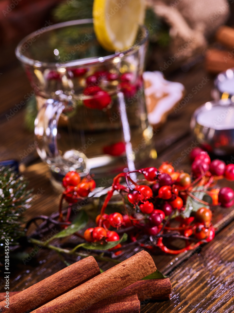 Christmas background with mug decoration lemon slice hot drink . Cinnamon sticks in foreground. Sharpness is on cinnamon sticks.