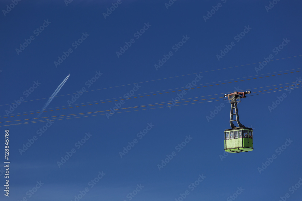 Cable car with blue sky in background and a plane flying Cable car with blue sky in background and a plane flying