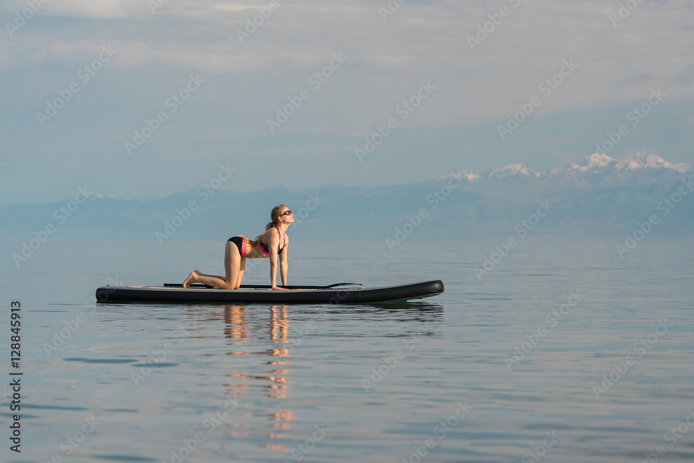 woman doing yoga on paddle board