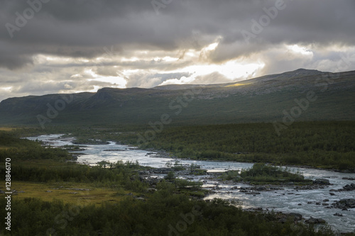 Sunset creates peaceful scenery with cloudscape and thundering river and forest landscape