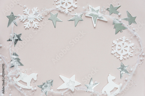 Christmas frame of white christmas decoration: snowflakes, stars, Christmas trees and toy; rocking horse on pink background. Flat lay composition for greeting card, websites, social media, magazines