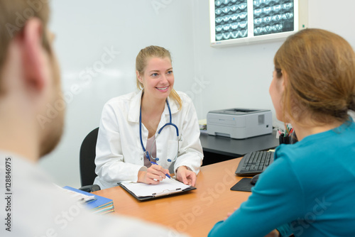 Wallpaper Mural excited couple talking to a doctor sitting at desk Torontodigital.ca