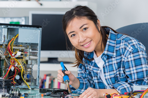 Wallpaper Mural young woman fixing a desktop computer seated at a table Torontodigital.ca