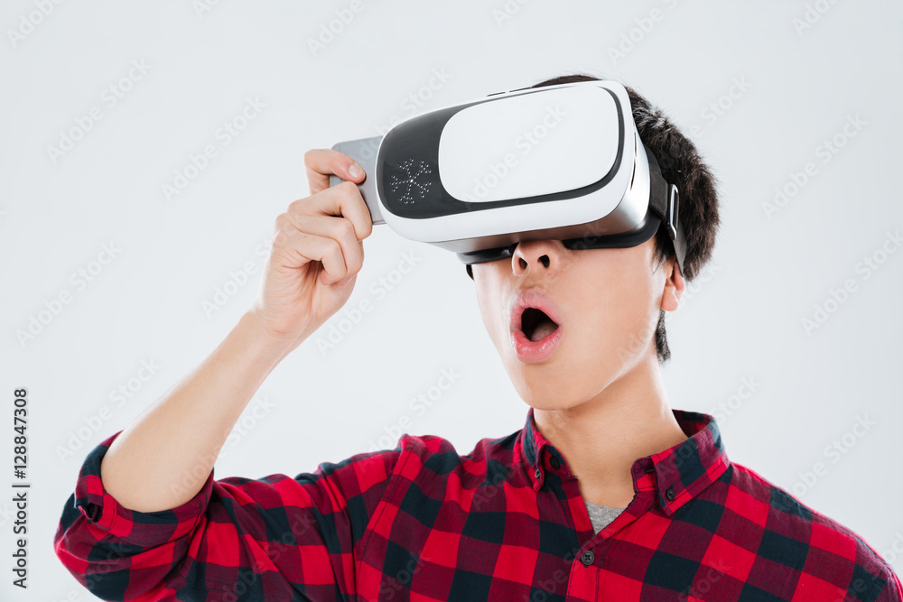 Asian man wearing virtual reality device while holding phone Asian man wearing virtual reality device while holding phone