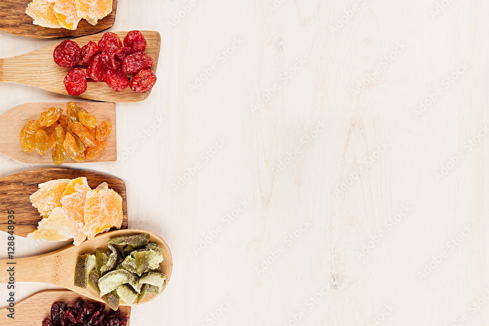 Assortment of dried fruits on wooden spoons on white background. Decorative border of dry exotic fruit. Top view. Assortment of dried fruits on wooden spoons on white background. Decorative border of dry exotic fruit. Top view.