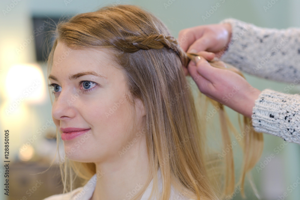 Naklejka premium a hairdresser braiding a client