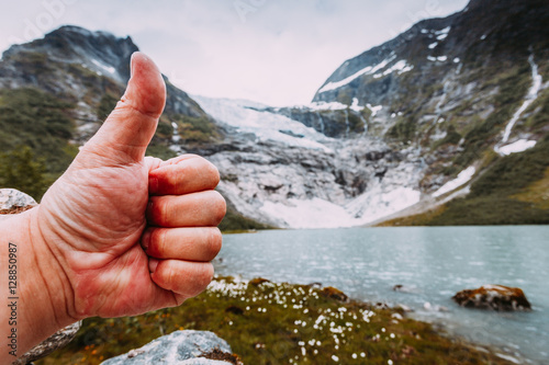 Male hand showing like with thumb up on mountains background photo