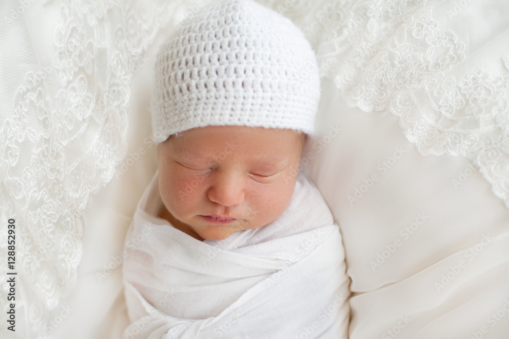 Newborn baby 7 days wrapped in white diaper and hat and sleeping Newborn baby 7 days wrapped in white diaper and hat and sleeping