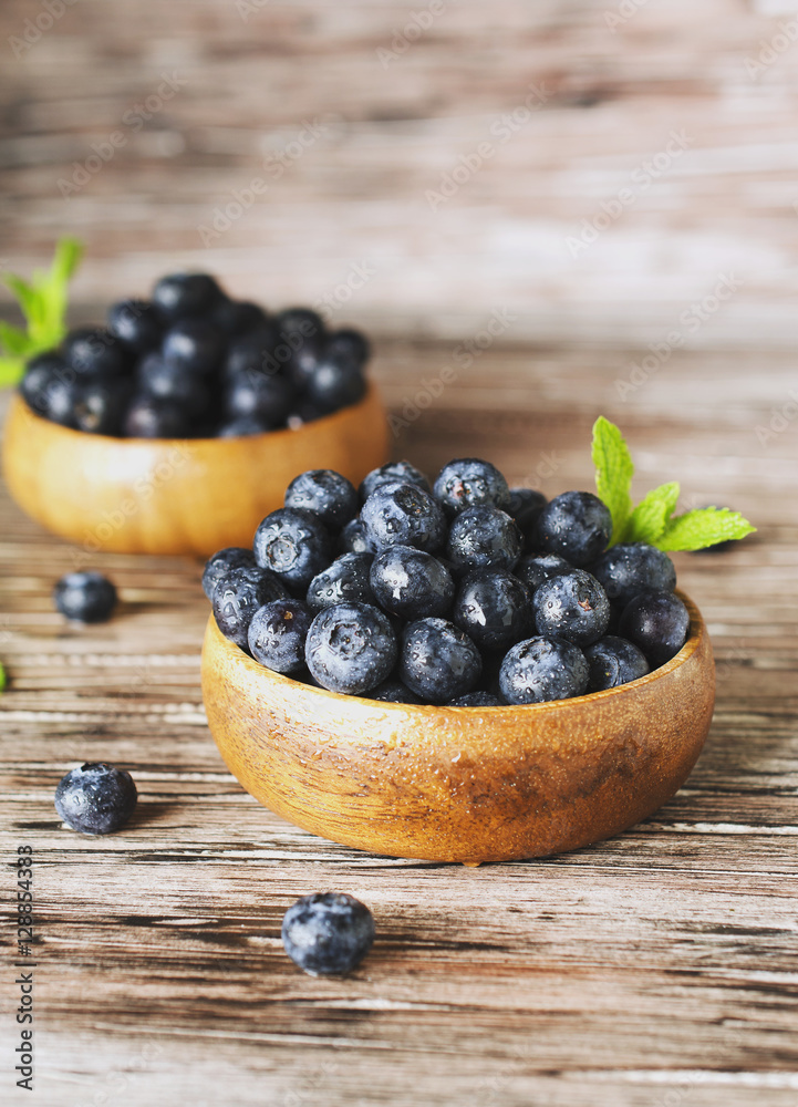 fresh bilberries or blueberries in small wooden bowls, selective focus fresh bilberries or blueberries in small wooden bowls, selective focus