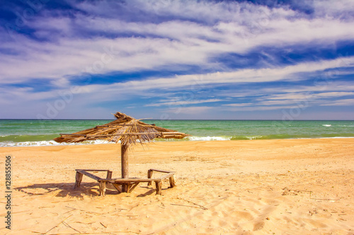 deserted beach, wooden umbrella, sand and sky