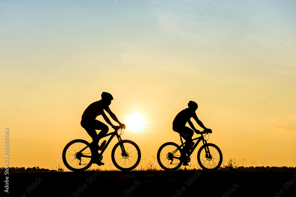 Silhouette of cyclist with friend motion on sunset background Silhouette of cyclist with friend motion on sunset background