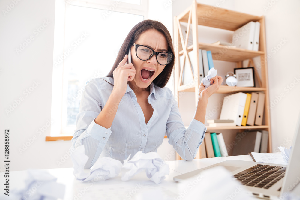 Confused businesswoman screaming while talking by phone