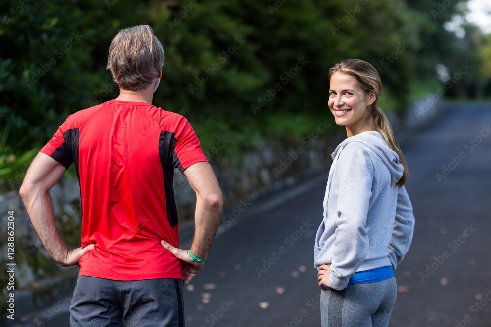Athletic couple standing with hands on hip on the road