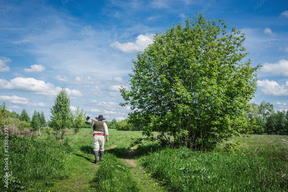 traveler in old clothes with a knapsack on a country road traveler in old clothes with a knapsack on a country road