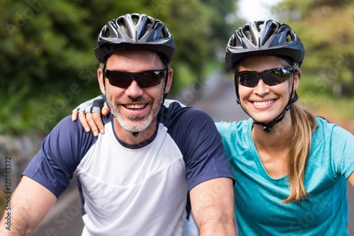 Athletic couple wearing helmets while riding bicycle