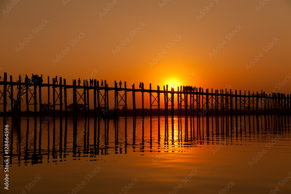 U Bein Bridge at sunset with people crossing Ayeyarwady River, M