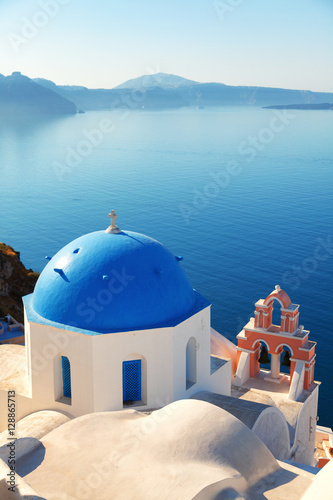 Blue dome church in Oia, Santorini, Greece. Sea and volcano on b