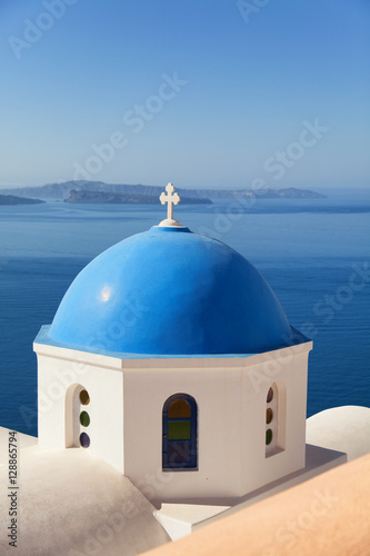 Blue dome church in Oia, Santorini, Greece. Sea and volcano on b