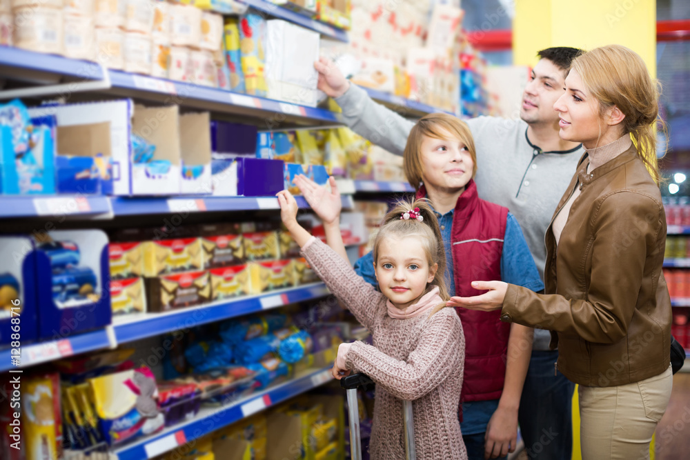 Parents with two kids choosing crispy flakes in shop