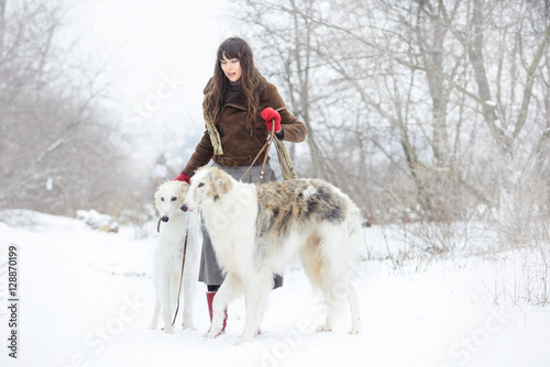 girl with two greyhounds in the winter, falling snow