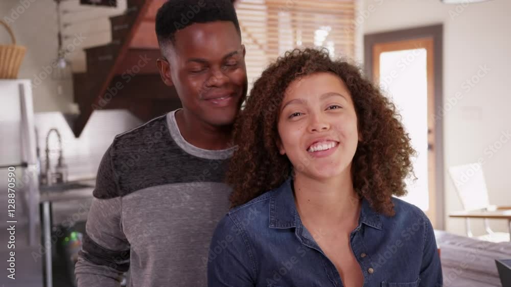 Young African American man and woman talk in their modern kitchen. Millennial black couple poses in their upscale home Young African American man and woman talk in their modern kitchen. Millennial black couple poses in their upscale home