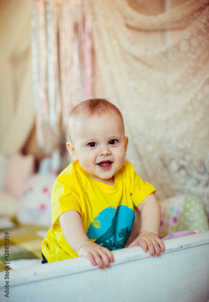 cute little boy in a yellow t-shirt sits on the bed cute little boy in a yellow t-shirt sits on the bed