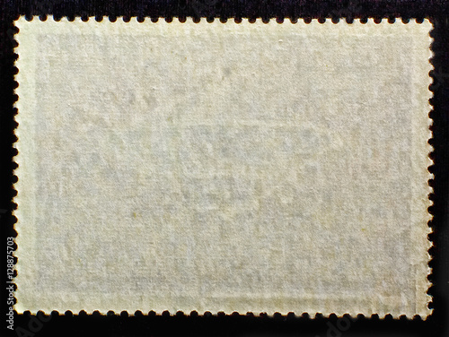 Old posted stamp reverse  side with the edge of the sheet. Texture of paper.