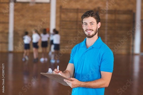 Fototapeta Naklejka Na Ścianę i Meble -  Portrait of sports teacher writing on clipboard
