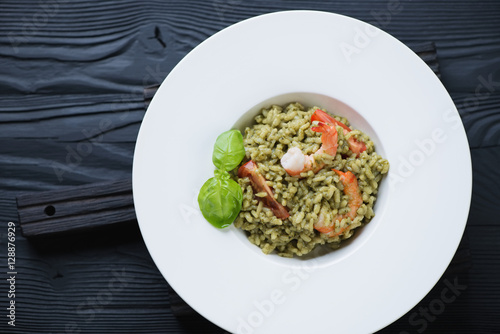 White plate with spinach risotto over black wooden background