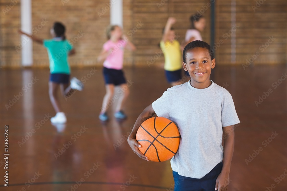 Fototapeta premium Boy standing with ball in basketball court