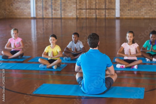 School kids and teacher meditating during yoga class