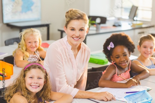 Teacher helping kids with their homework in classroom © WavebreakMediaMicro