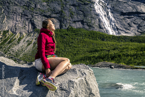 Young woman is sitting on the stone, Briksdalsbreen, Norway