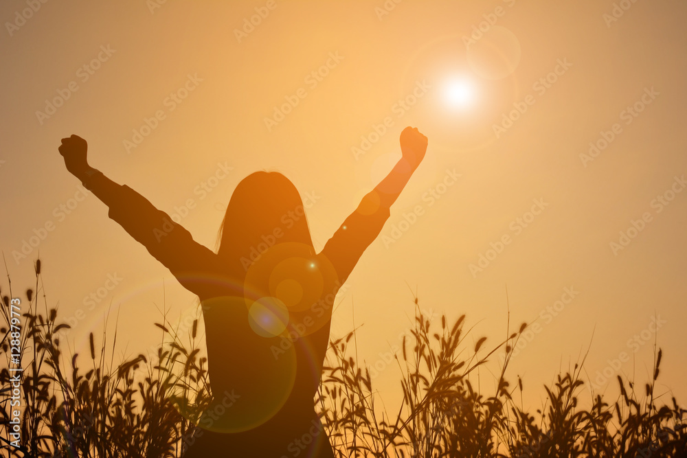 Silhouette of happy women open hand in grass field at the sky sunset