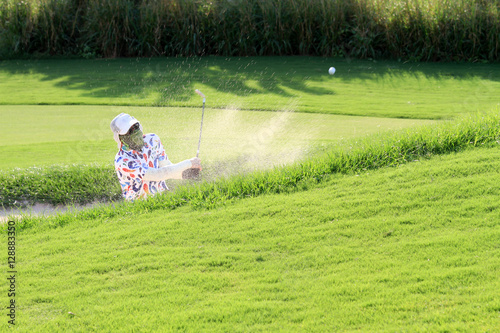 The men golfers hit golf balls off the sand motion blur