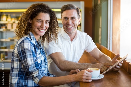 Portrait of happy couple using digital tablet in café