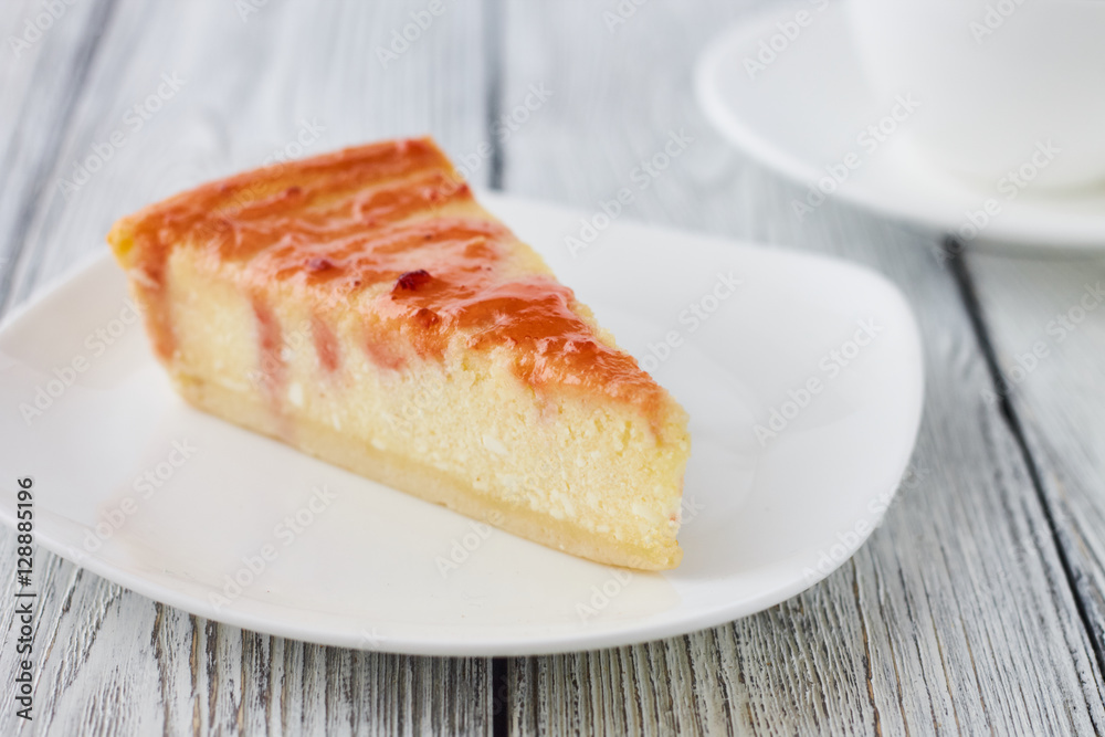Slice of the New York cheesecake on a white plate on a wooden background Slice of the New York cheesecake on a white plate on a wooden background