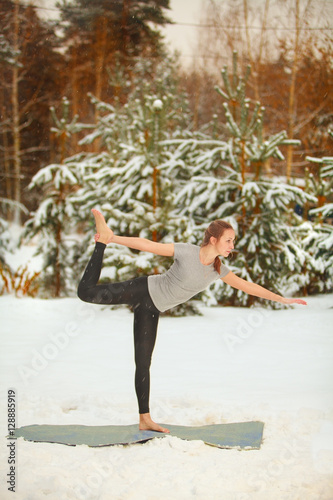 beautiful woman doing yoga outdoors in snow photo