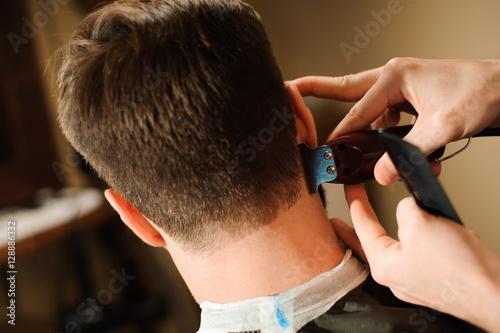 Master cuts hair and beard of men in the barbershop