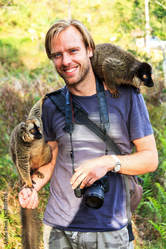 Male tourist having fun with a lemurs on his shoulders in Madagascar