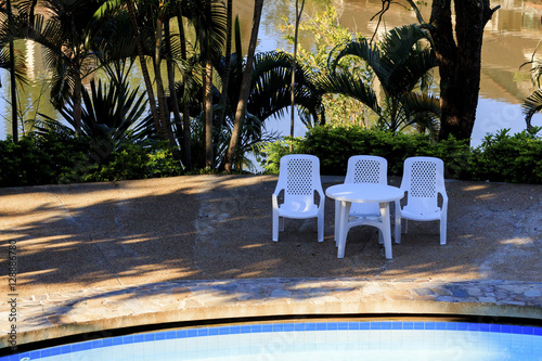 Three chairs beside pool.