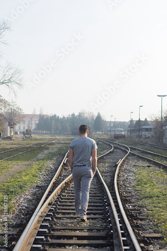 Man walking on railroad tracks photo