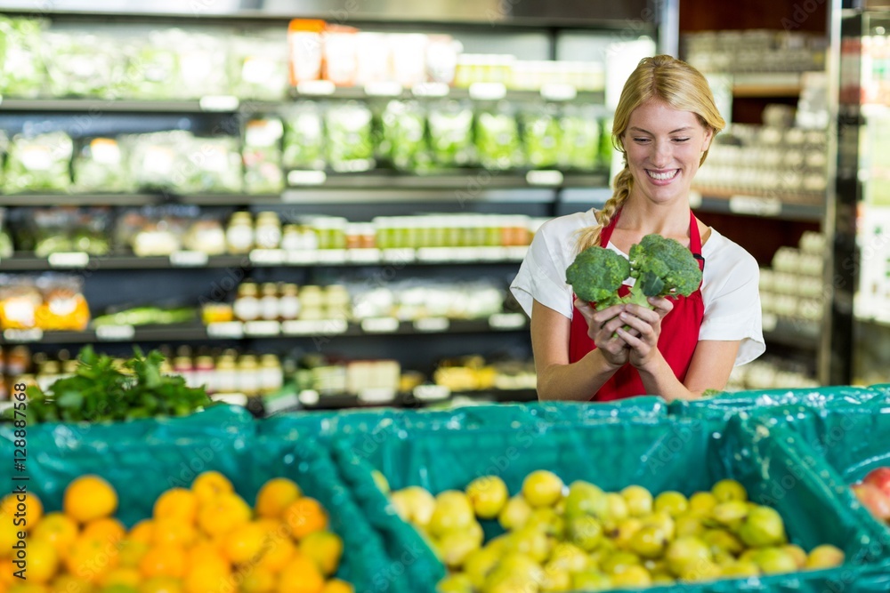 Female staff holding broccoli in organic section