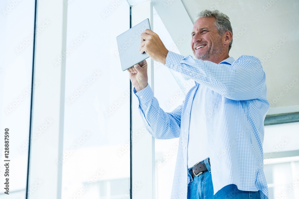 Low angle view of happy mature man holding tablet