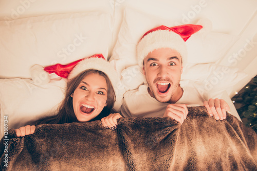 Top view of cute amased surprised couple in santa hats screaming photo