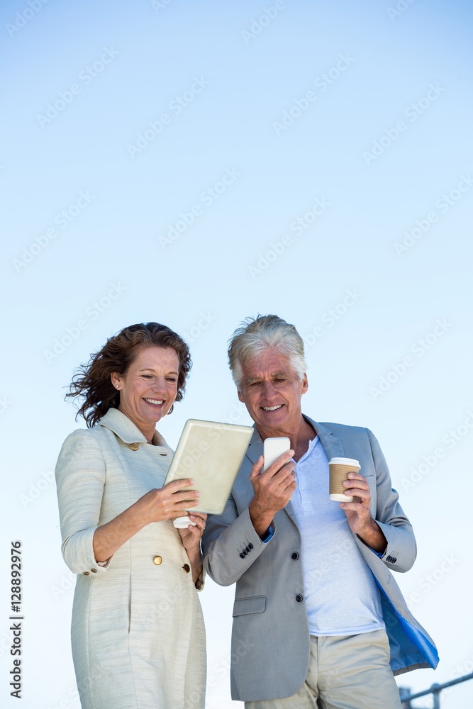 Smiling couple using digital tablet and mobile phon Smiling couple using digital tablet and mobile phon